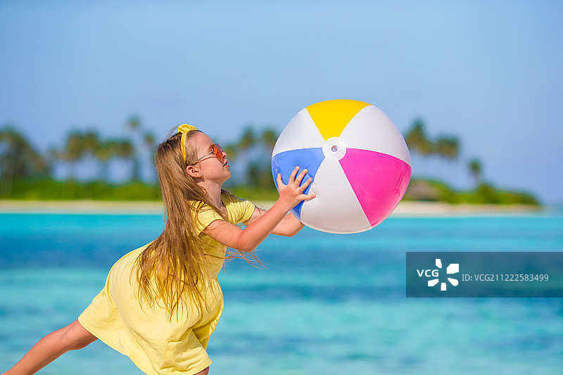 在海滩上玩气球的可爱小女孩图片素材