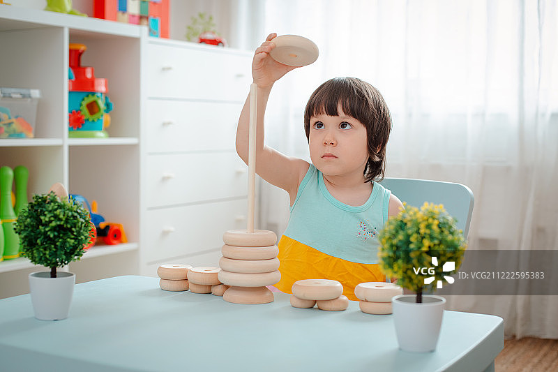 小女孩收集木制未上漆金字塔安全天然儿童玩具图片素材