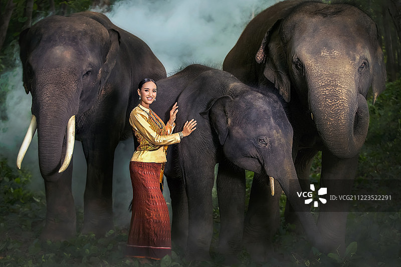 身穿泰国民族服装与大象站在一起的年轻女人们图片素材