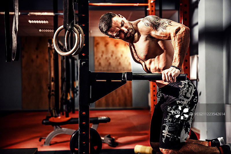 健壮的肌肉男在Crossfit健身房里在不平的单杠上做俯卧撑图片素材
