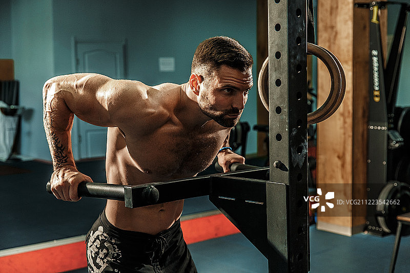 健壮的肌肉男在健身房的不平衡杠上做俯卧撑图片素材