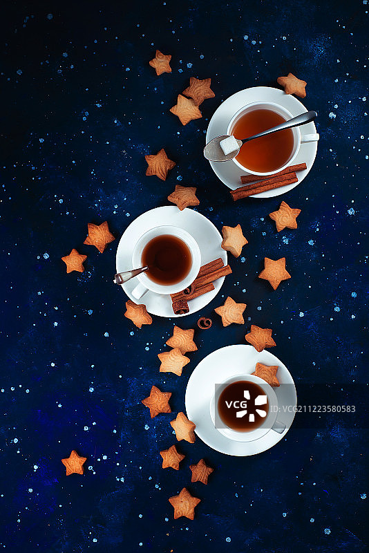 星空背景下的茶歇：星形饼干与白色瓷杯图片素材
