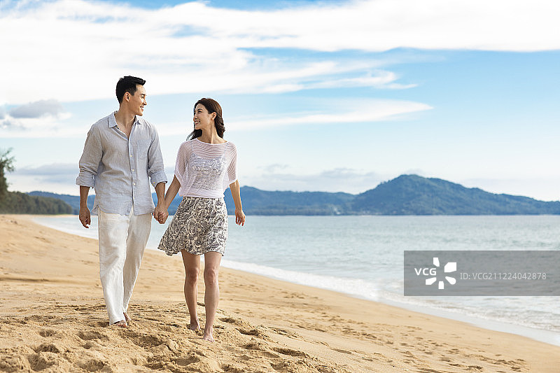 快乐的年轻夫妇在沙滩散步图片素材