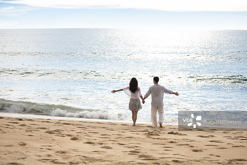 快乐的年轻夫妇在沙滩散步图片素材