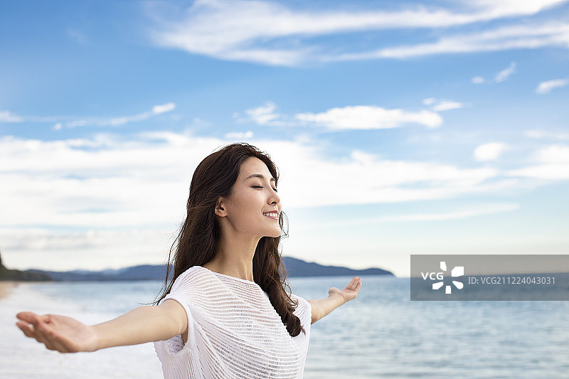 年轻女性在海边张开双臂图片素材