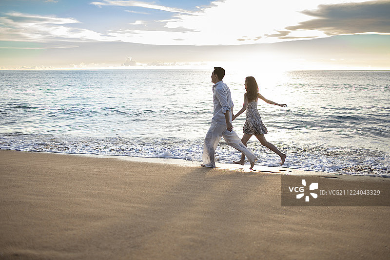 快乐的年轻夫妇在沙滩奔跑图片素材