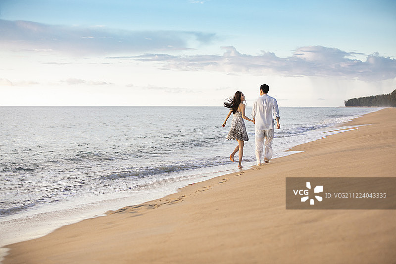 快乐的年轻夫妇在沙滩奔跑图片素材