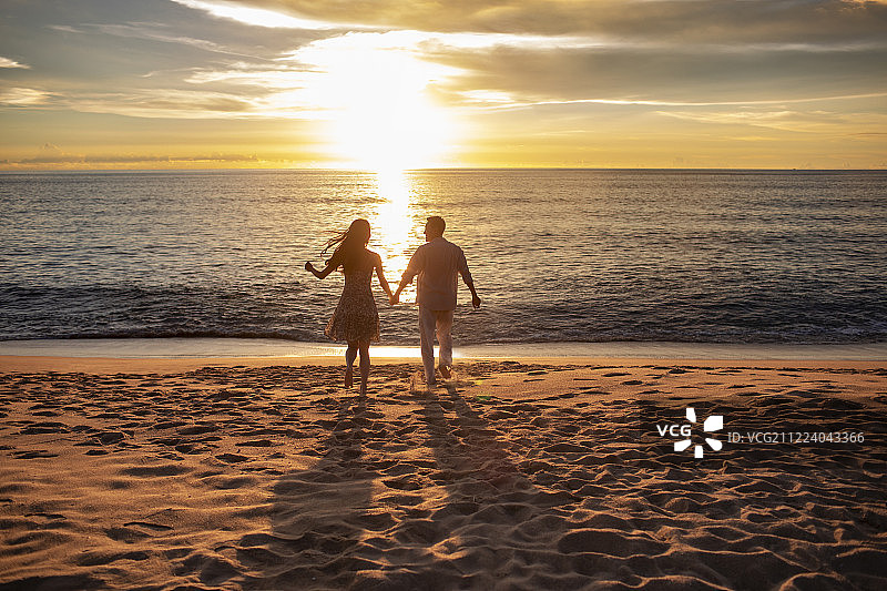 快乐的年轻夫妇在沙滩奔跑图片素材