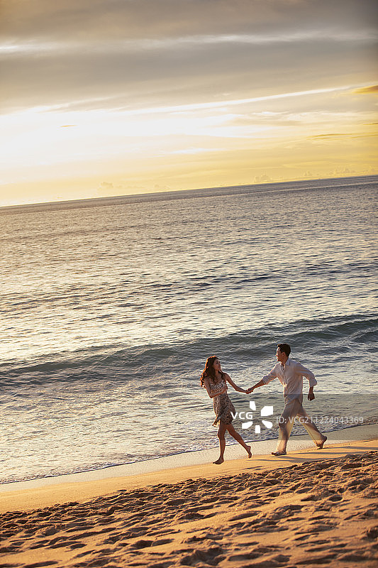 快乐的年轻夫妇在沙滩奔跑图片素材