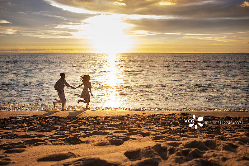 快乐的年轻夫妇在沙滩奔跑图片素材