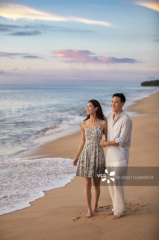 快乐的年轻夫妇在沙滩散步图片素材