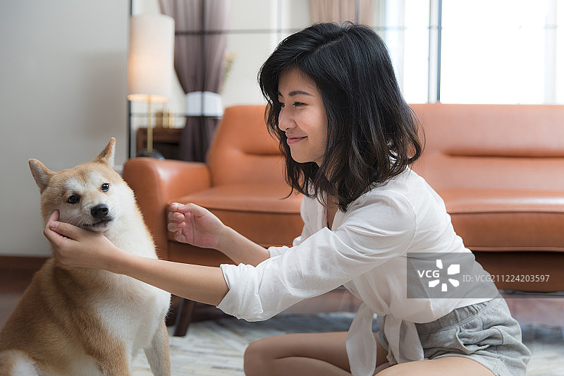青年女子和小狗在客厅嬉戏玩耍图片素材