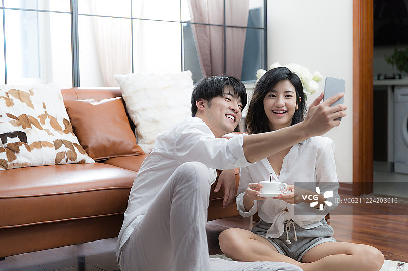 青年情侣在客厅拿着手机自拍图片素材