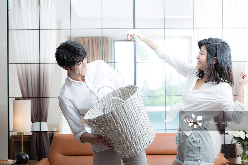 甜蜜情侣一起在客厅做家务嬉戏打闹图片素材