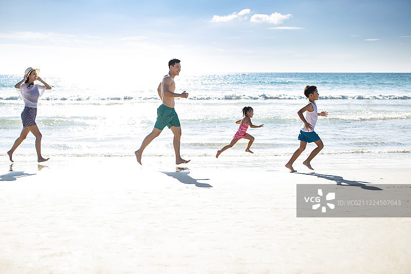 快乐的年轻家庭在沙滩奔跑图片素材