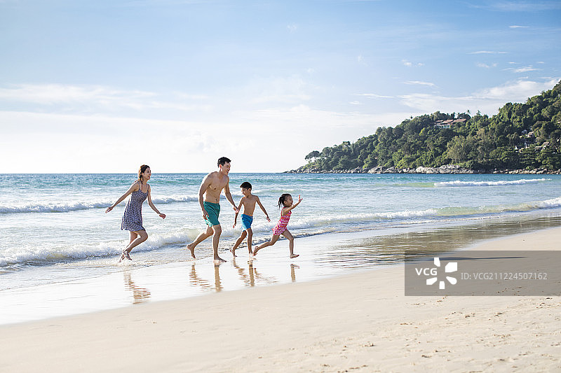 快乐的年轻家庭在沙滩奔跑图片素材