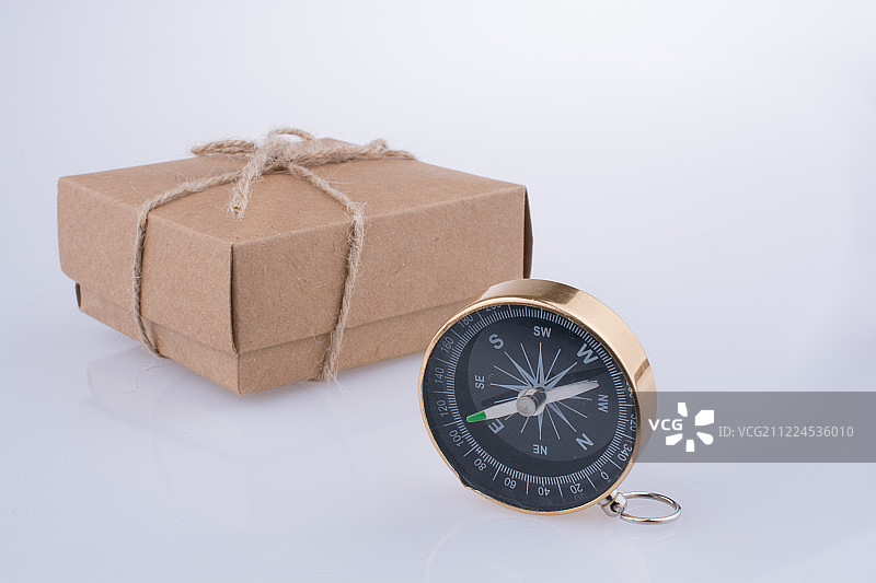 白色背景下带有纸板盒的导航罗盘特写图片素材