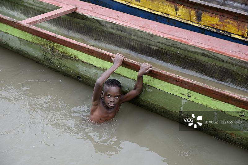 男孩在河边的船旁玩耍，里奥安达格达，巴加多，乔科省，哥伦比亚，南美洲图片素材