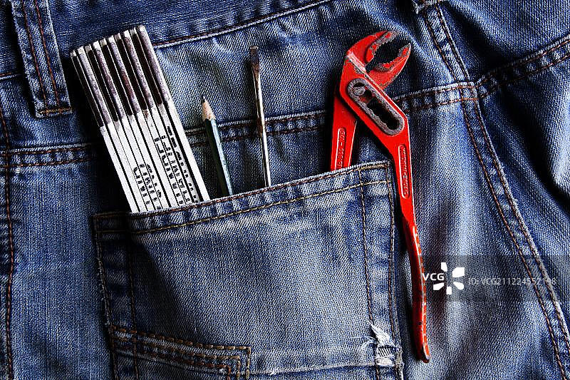 牛仔裤口袋里的尺子、铅笔、螺丝刀、管钳图片素材
