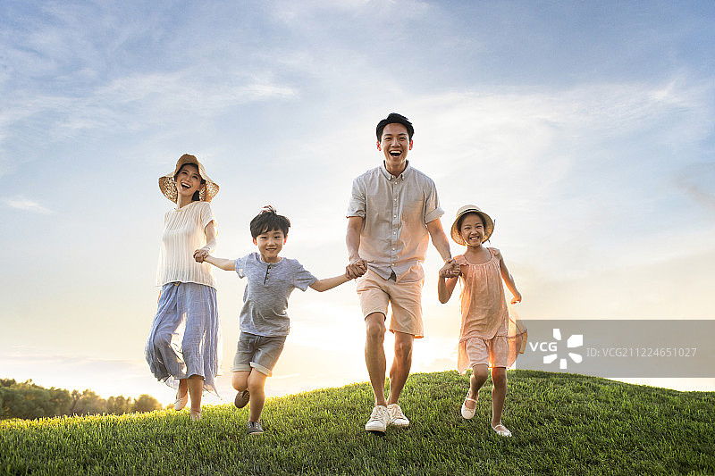 年轻家庭在草地上奔跑图片素材
