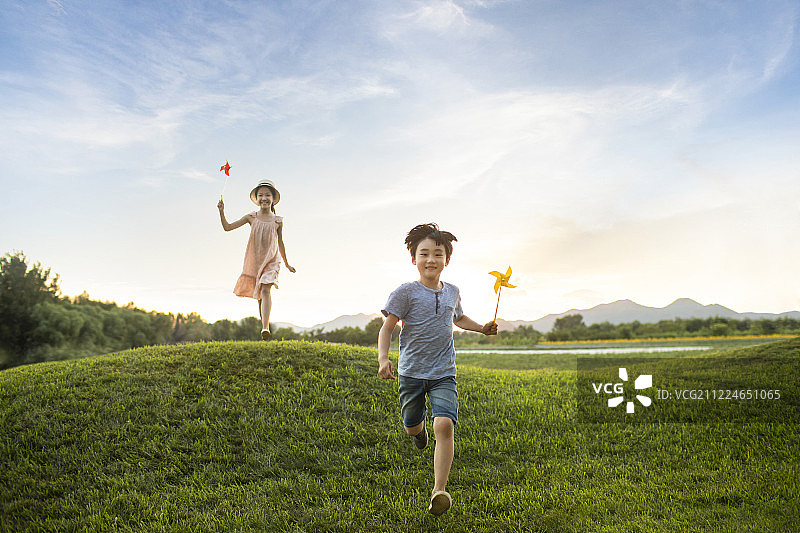 姐弟俩在草地上玩风车玩具图片素材