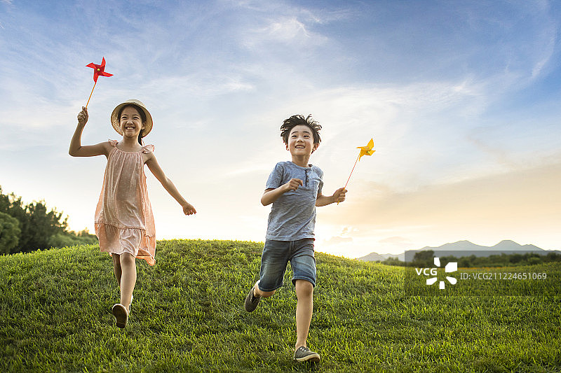 姐弟俩在草地上玩风车玩具图片素材