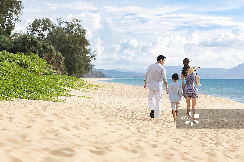 快乐的年轻家庭在沙滩漫步图片素材