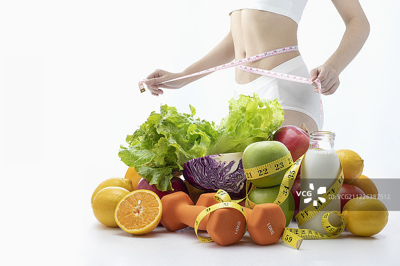 减肥时测量腰围的窈窕女性与五色蔬果图片素材