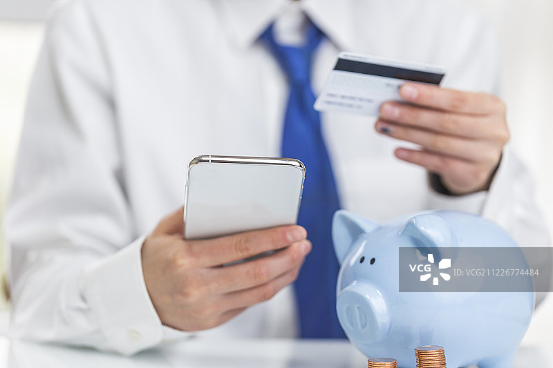 商务人士拿着手机和银行卡充值图片素材