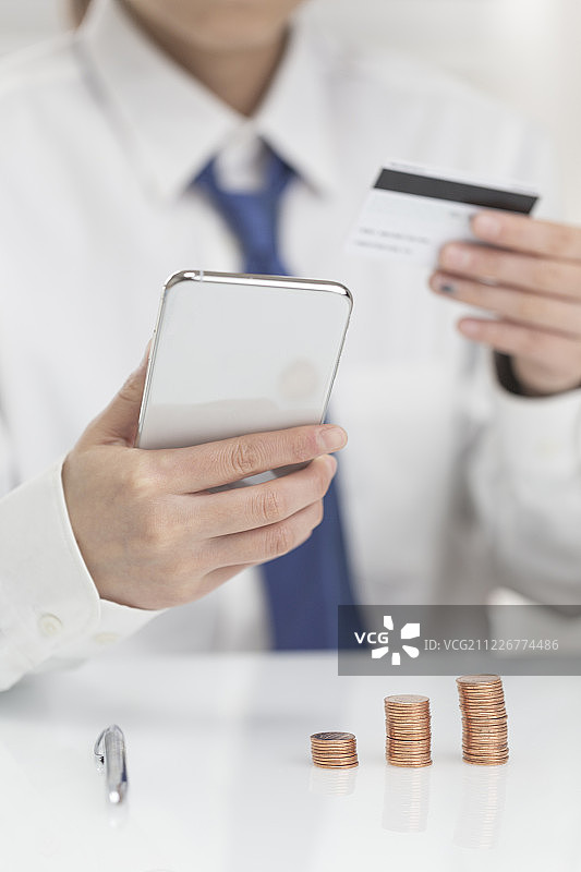 商务人士拿着手机和银行卡充值图片素材