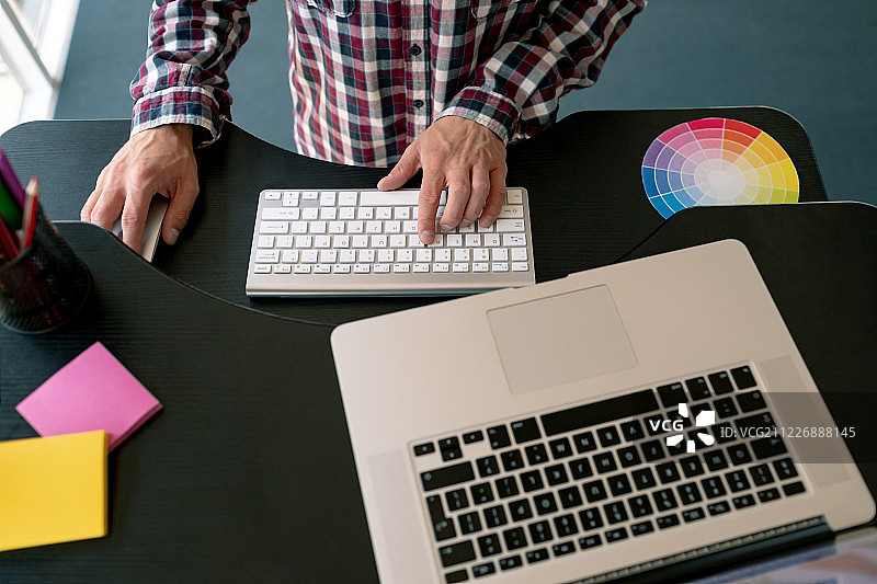 在办公室办公桌前使用笔记本电脑的男图形设计师图片素材