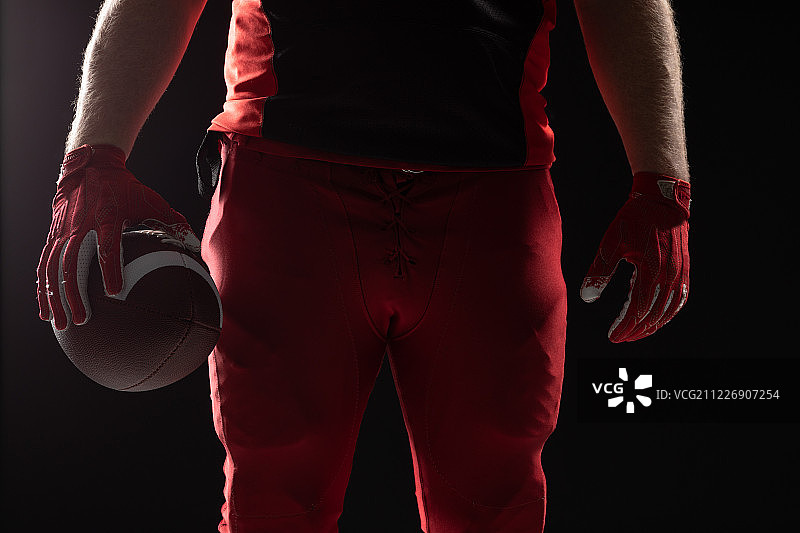 美式橄榄球运动员手持橄榄球站立图片素材