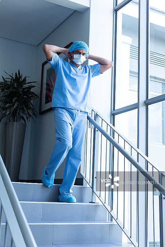 戴着外科口罩的男外科医生走下医院楼梯图片素材