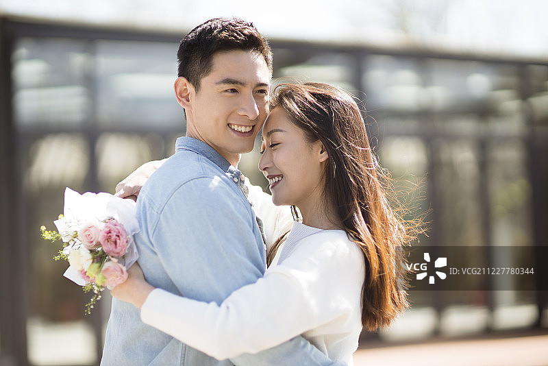 年轻女子手拿鲜花拥抱男朋友图片素材