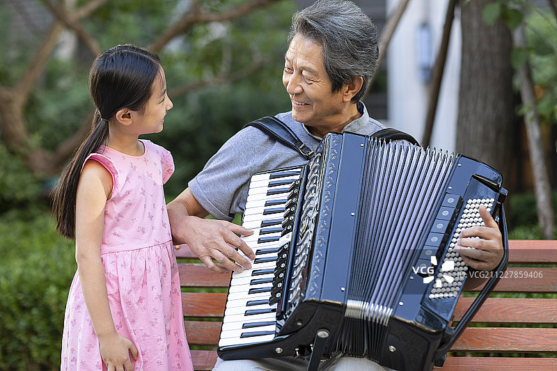 祖孙俩在公园弹手风琴图片素材