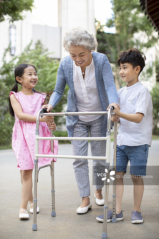 兄妹俩帮助奶奶用助行器走路图片素材