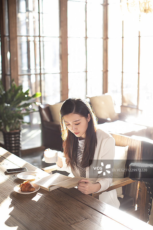 年轻商务女士在咖啡店看书图片素材