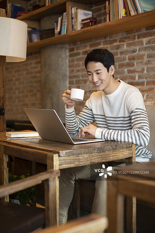 年轻男士在咖啡店使用笔记本电脑图片素材