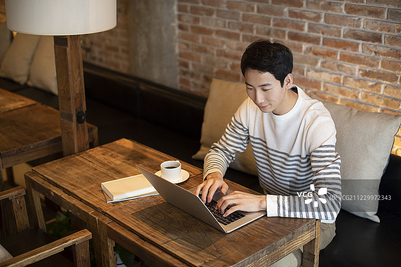 年轻男士在咖啡店使用笔记本电脑图片素材