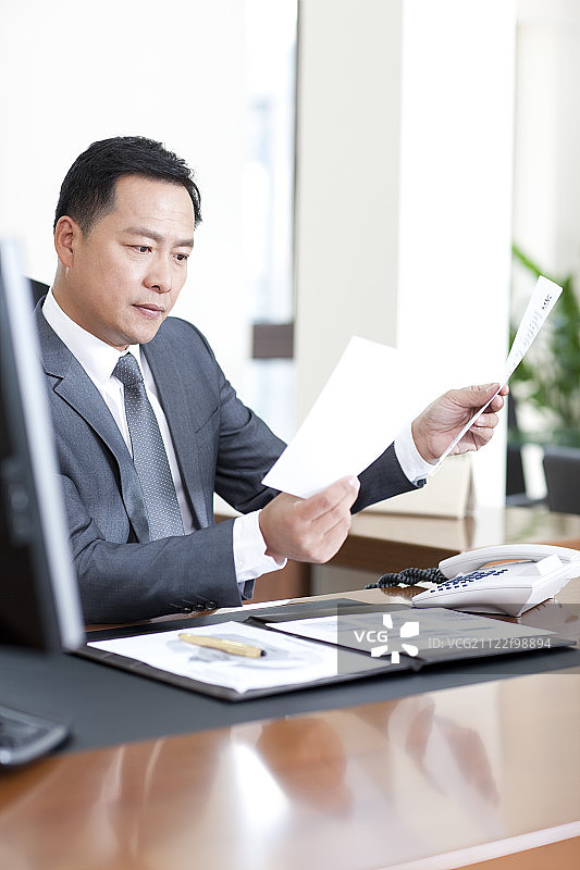 中年商务男士仔细看文件图片素材