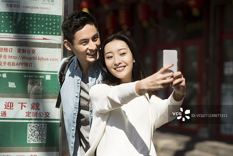 年轻情侣使用手机拍照图片素材