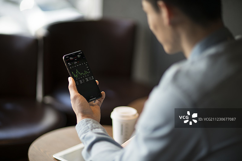 年轻男子使用手机看股市图片素材