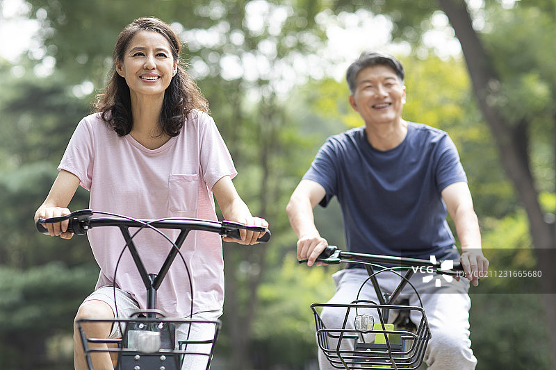 快乐的成熟夫妇在公园骑自行车图片素材