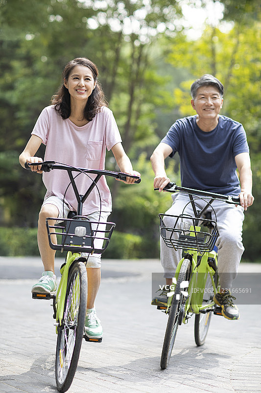 快乐的成熟夫妇在公园骑自行车图片素材