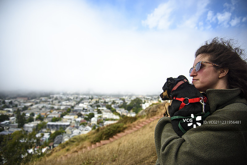 在加利福尼亚州旧金山坦克山上，女人抱着狗的侧视图图片素材