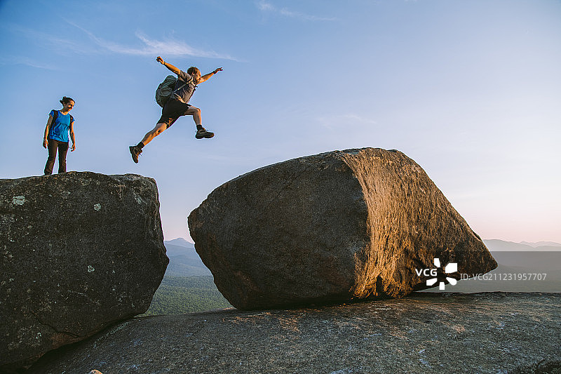 在美国纽约州阿迪朗达克山脉Pitchoff山徒步旅行时,男人跳过巨石的侧视图图片素材