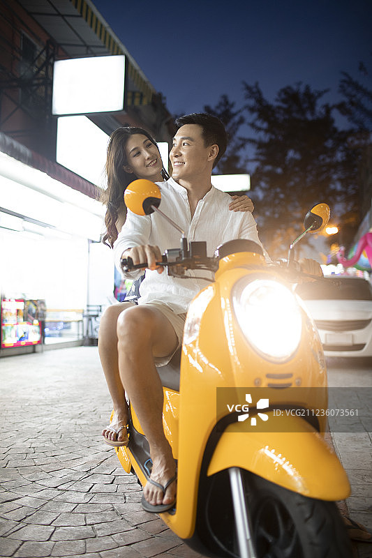 快乐的年轻情侣骑摩托逛夜市图片素材