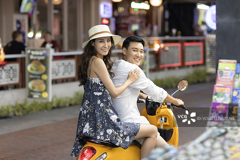 快乐的年轻情侣骑摩托逛夜市图片素材