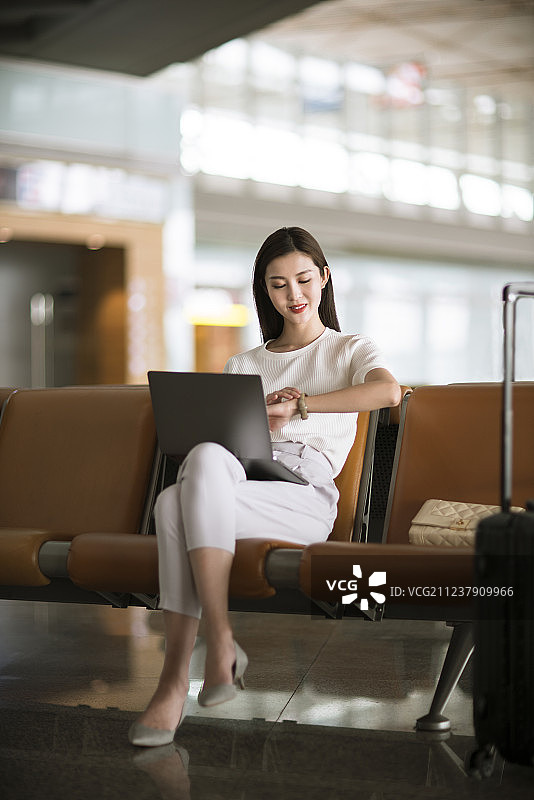 年轻女子在机场候机室使用笔记本电脑图片素材