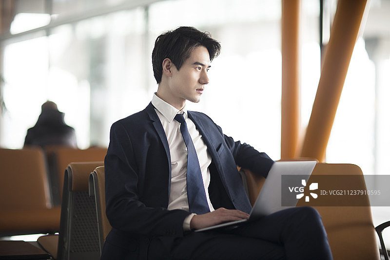 年轻商务男士在机场候机室使用笔记本电脑图片素材